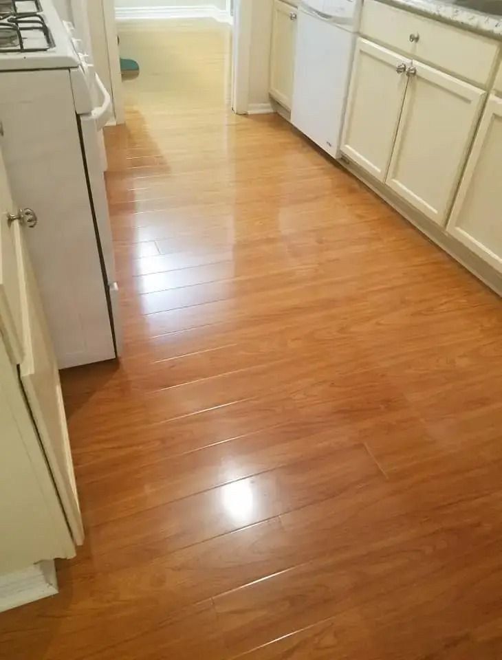 Narrow kitchen hallway with glossy wood floor and white cabinets on both sides