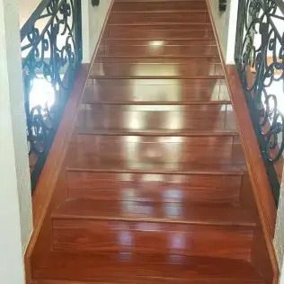 Wooden staircase with glossy brown steps and decorative black iron railings on both sides
