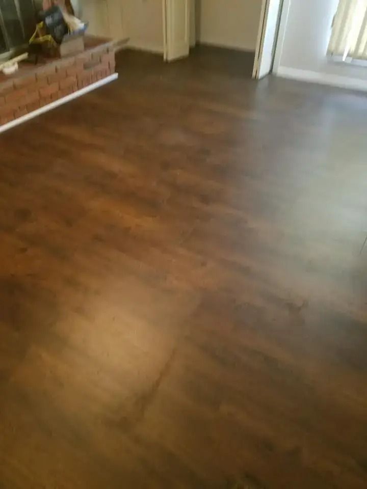 Empty room with dark wood flooring and a brick fireplace mantel on the left