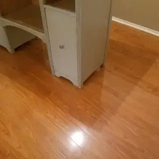 Wooden floor beside a white desk or cabinet in a room.