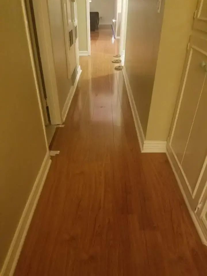 Narrow hallway with polished wood floor, beige walls, and doors lining both sides.