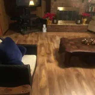 Cozy living room with wooden floor, fireplace, dark sofa, and coffee table.
