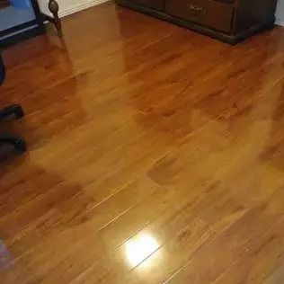Shiny hardwood floor in a room, reflecting light near dark wooden furniture.