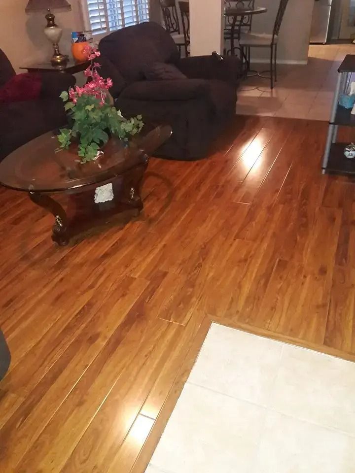 Living room with brown recliner, glass coffee table with flowers, and polished wood floor