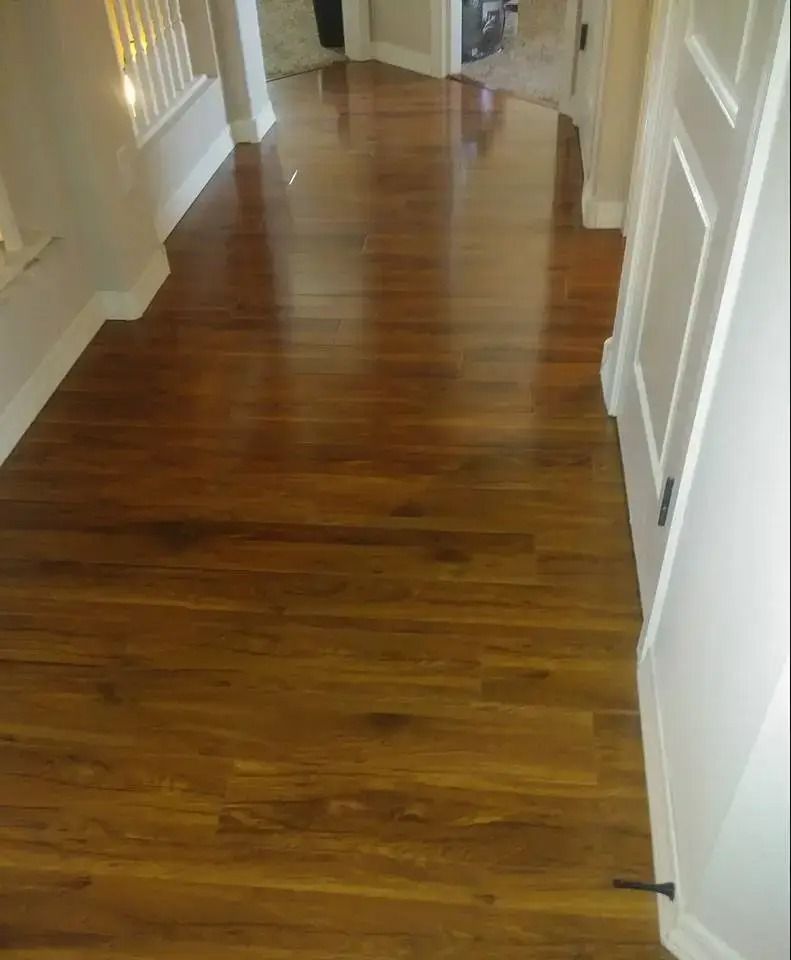 Empty hallway with polished hardwood floor and white walls, viewed from one end