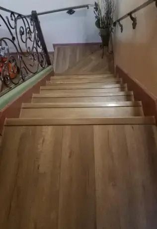 Wooden staircase with a decorative black metal railing in a home interior