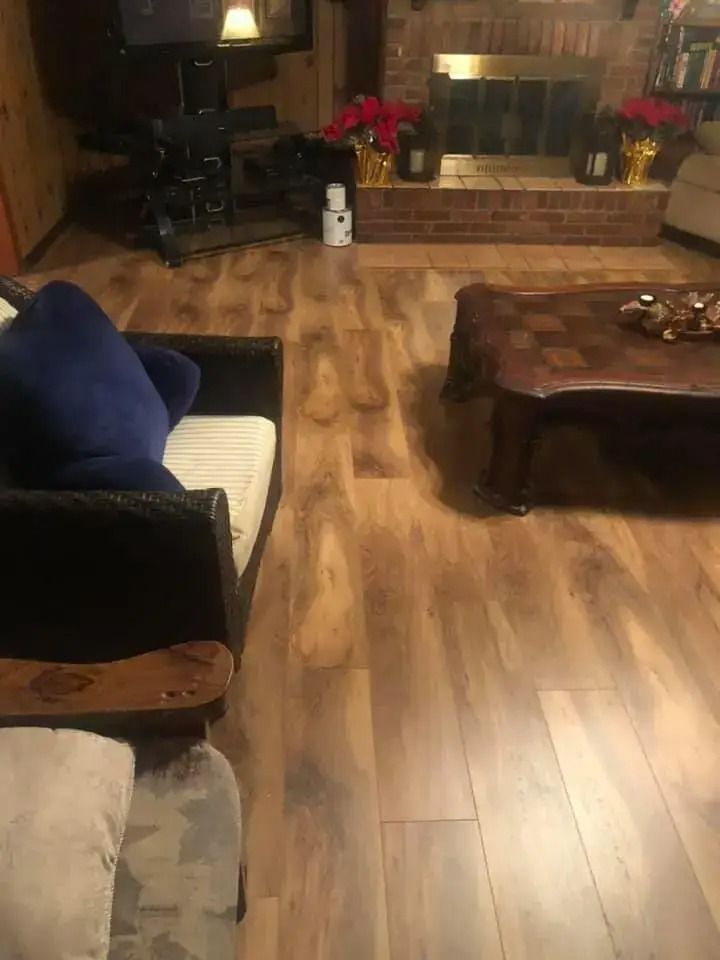 Cozy living room with wood floors, dark sofa, coffee table, and fireplace in warm lighting