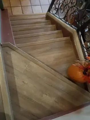 Wooden staircase with a black wrought-iron railing and a pumpkin decoration at the bottom stair.