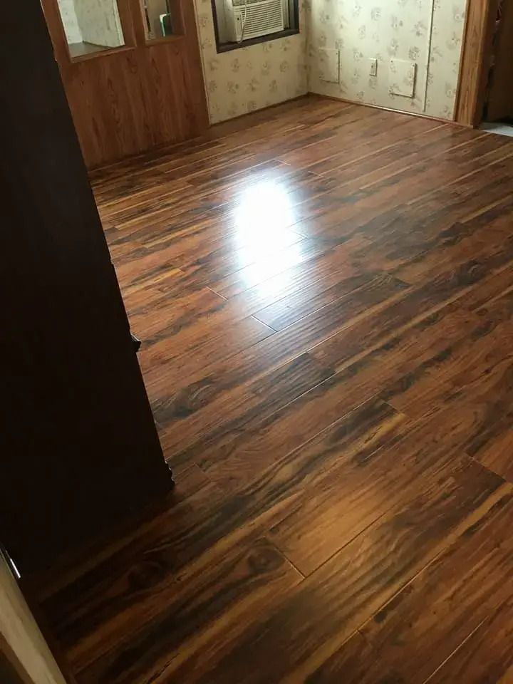 Empty room with glossy wood-pattern flooring and brown doors, viewed from a doorway.