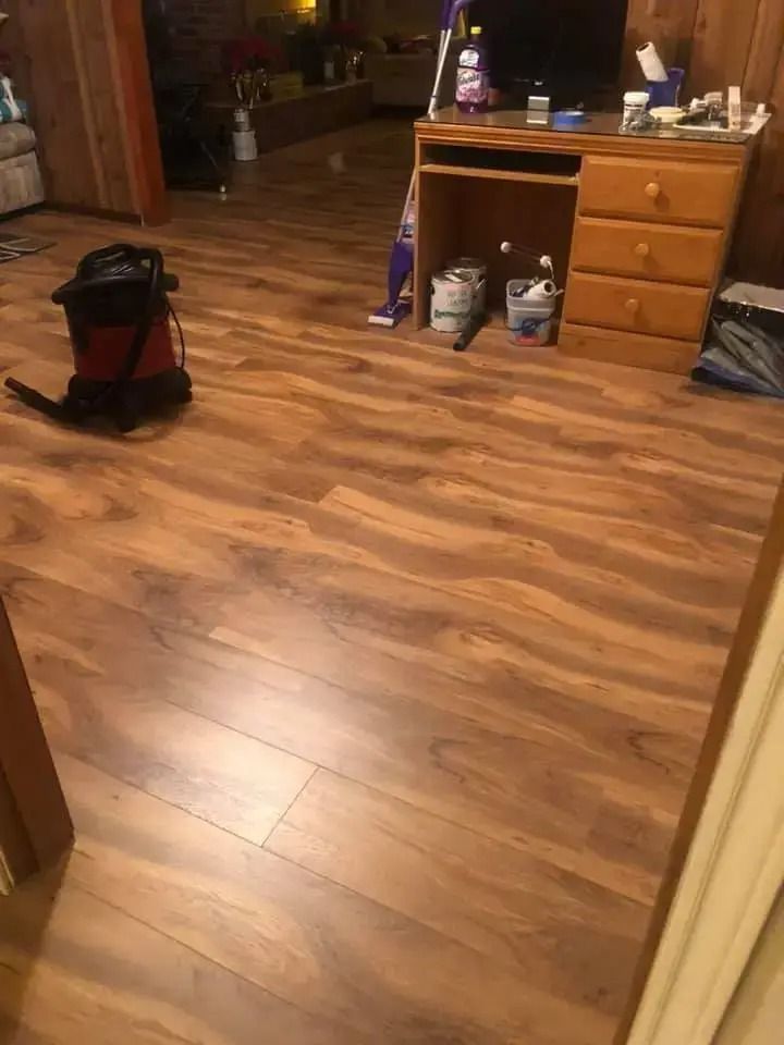 Wooden kitchen floor with a red vacuum cleaner and a dresser in a dimly lit room