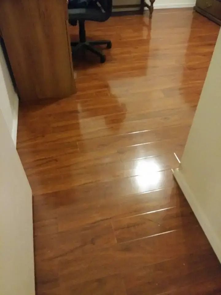 Shiny wooden hallway floor leading to a room with a desk and chair.
