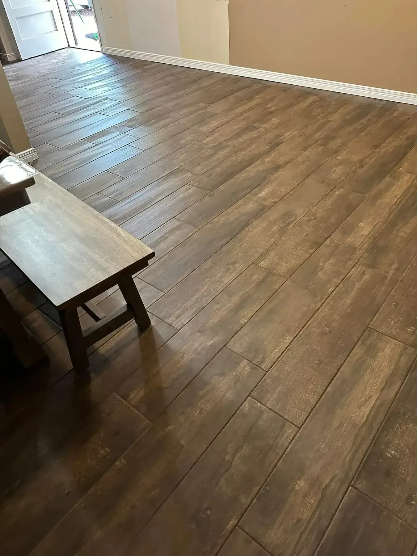 Empty room with wood-look flooring, white walls, and a bench in the foreground