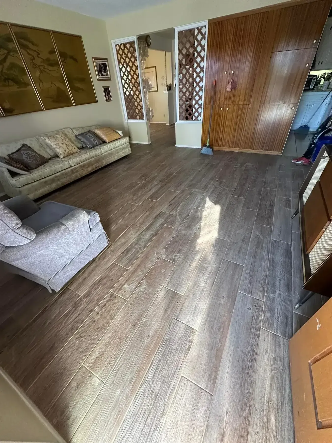 Small living room with wood-look floor, beige sofa, and large wooden closet doors.