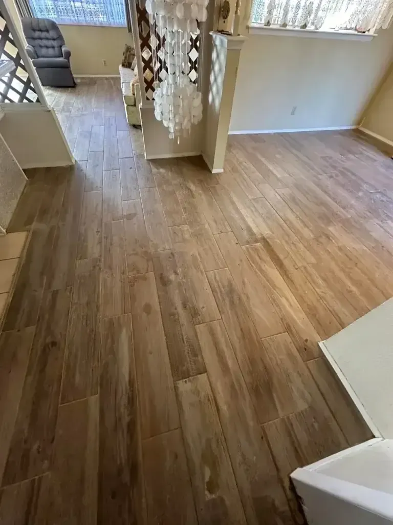 Empty room with light wood flooring, white walls, and a curtained doorway by a sunlit window.