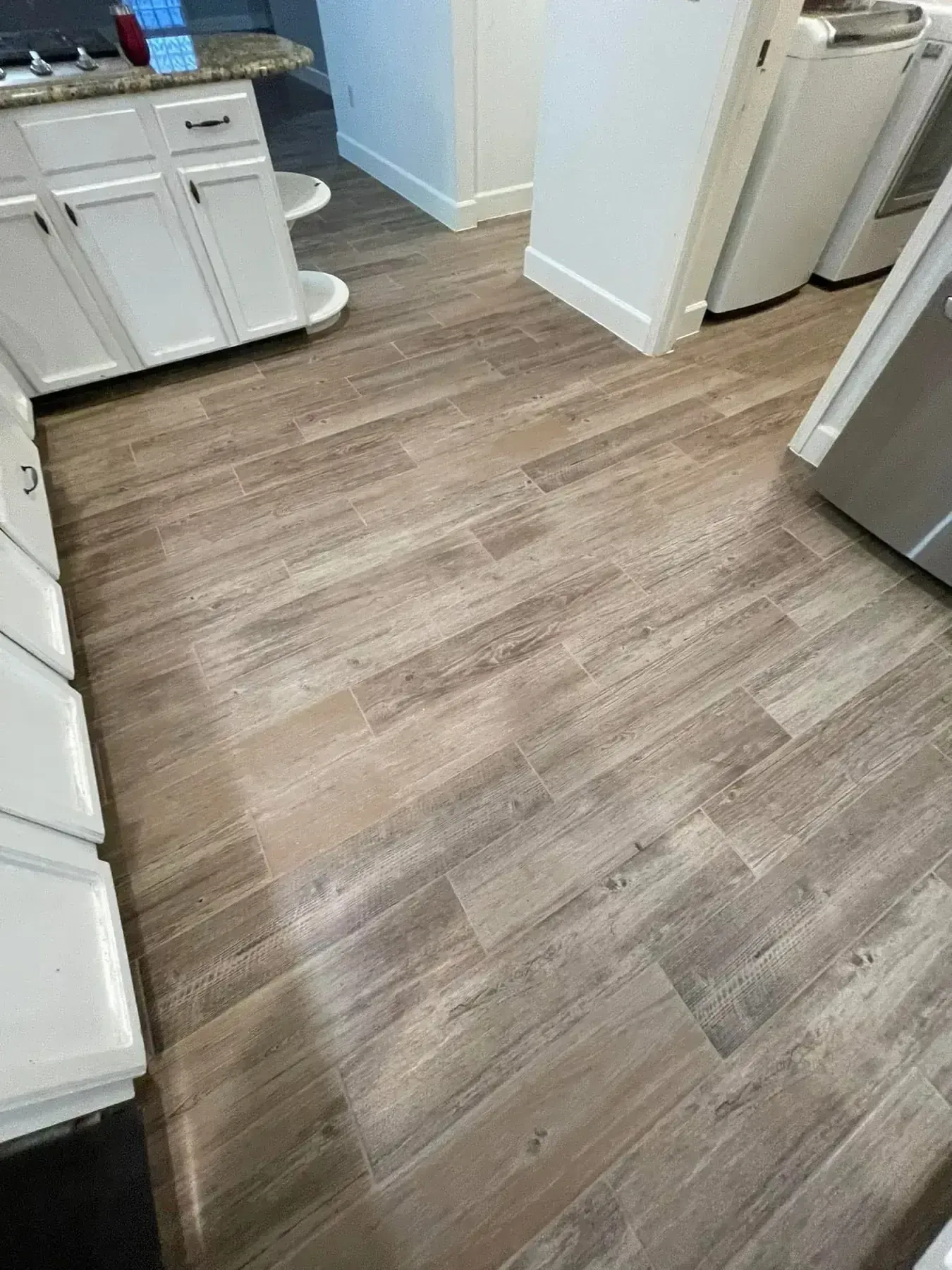 Kitchen with light wood flooring, white cabinets, and stainless steel appliances.