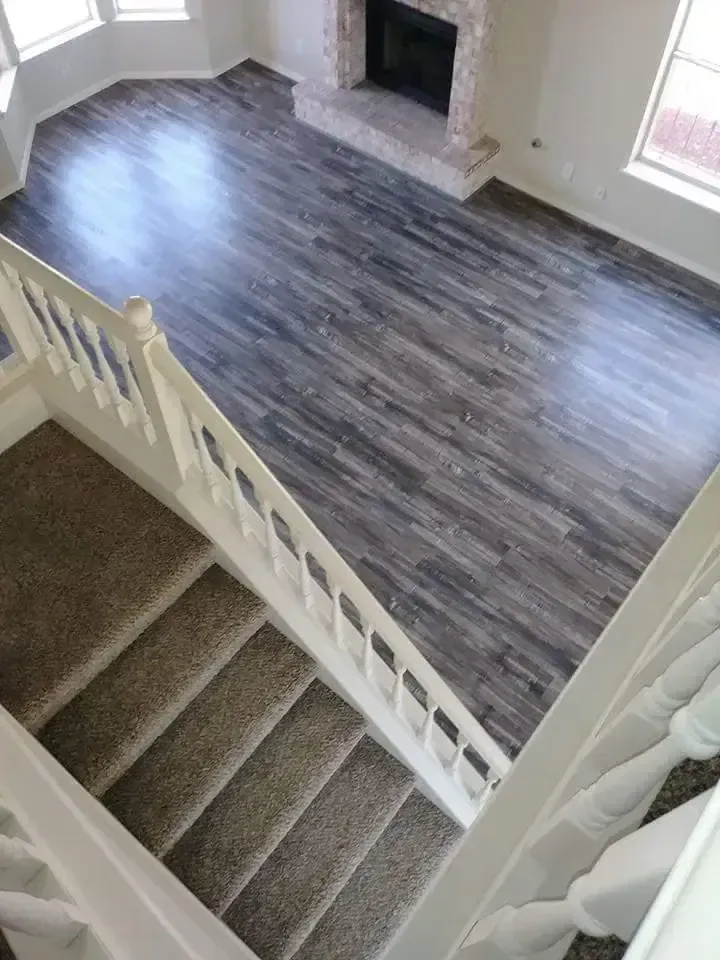 Staircase overlooking a living room with dark wood floors, gray walls, and a fireplace.