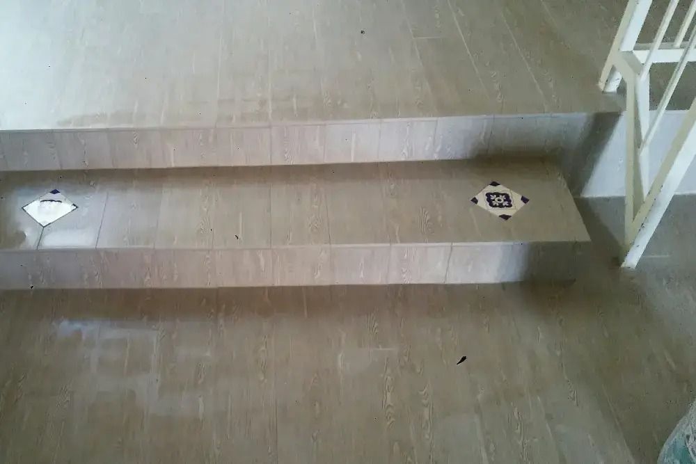 Indoor wooden ramp with a central raised strip and stair railings on one side.