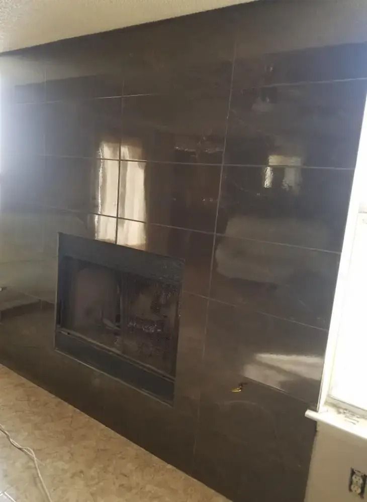 Dark tiled fireplace wall with a built-in rectangular fireplace opening and a window reflection.