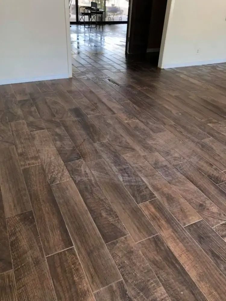 Empty room with wood-look tile flooring and a doorway to a dining area