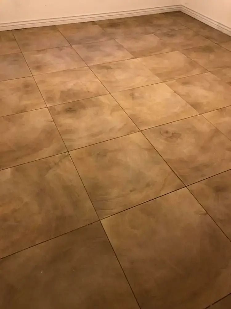 Empty tiled floor corner with beige tiles and white baseboards