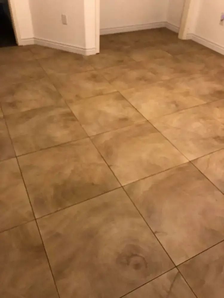 Beige tiled floor in a corner of an empty room with white walls.