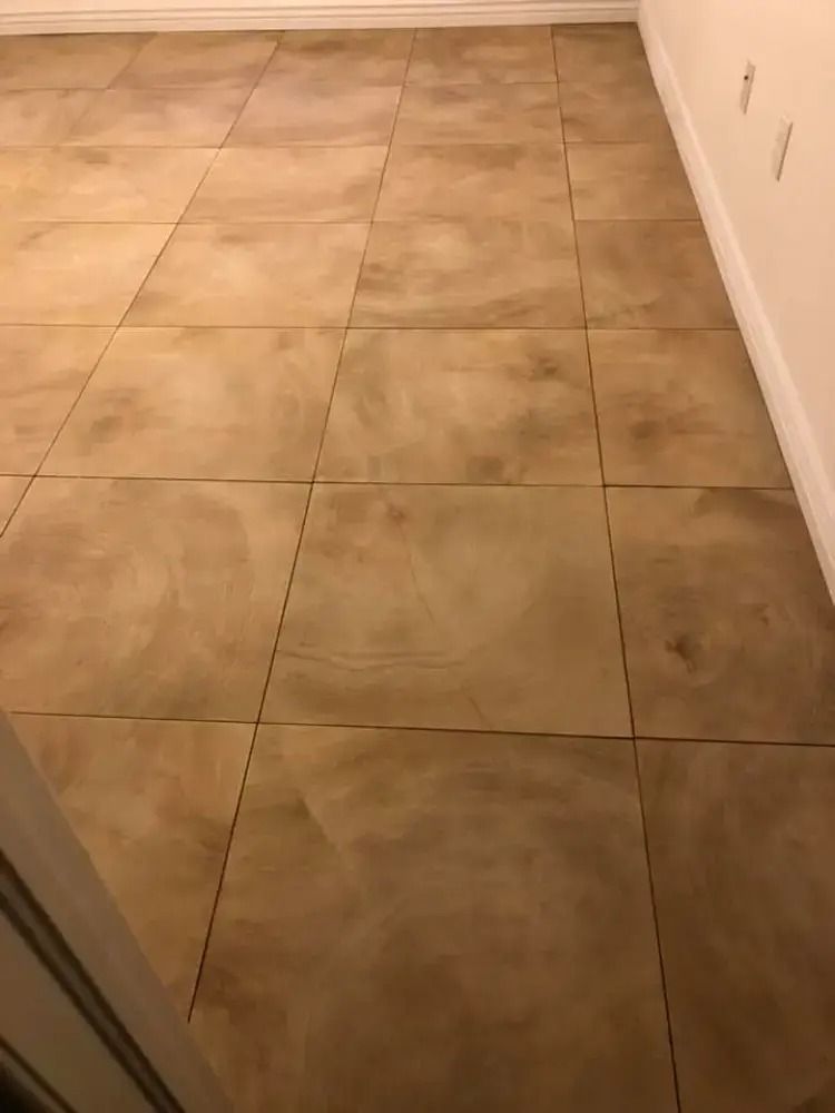 Empty tiled floor in a hallway with beige walls and a doorway on the left