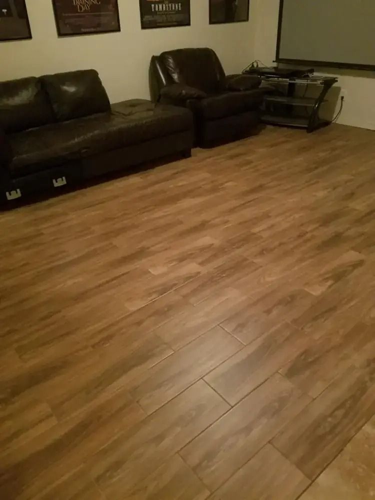 Living room with dark leather sofa, armchair, and glass side table on wood flooring