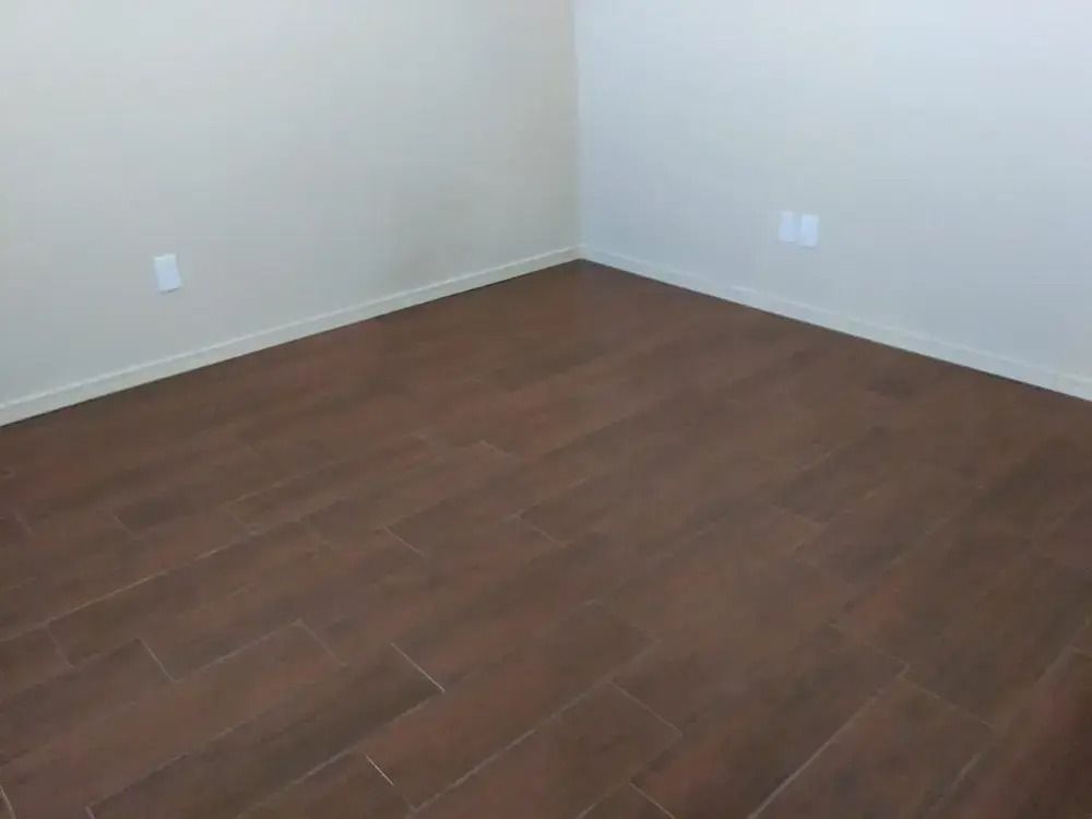 Empty room corner with brown wood floor and white walls