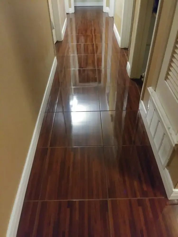 Narrow hallway with glossy wood-look tile floor and beige walls, viewed from one end.