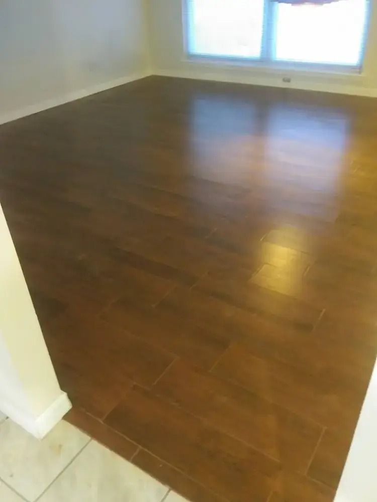 Empty room with dark wood floor, white walls, and a window letting in natural light