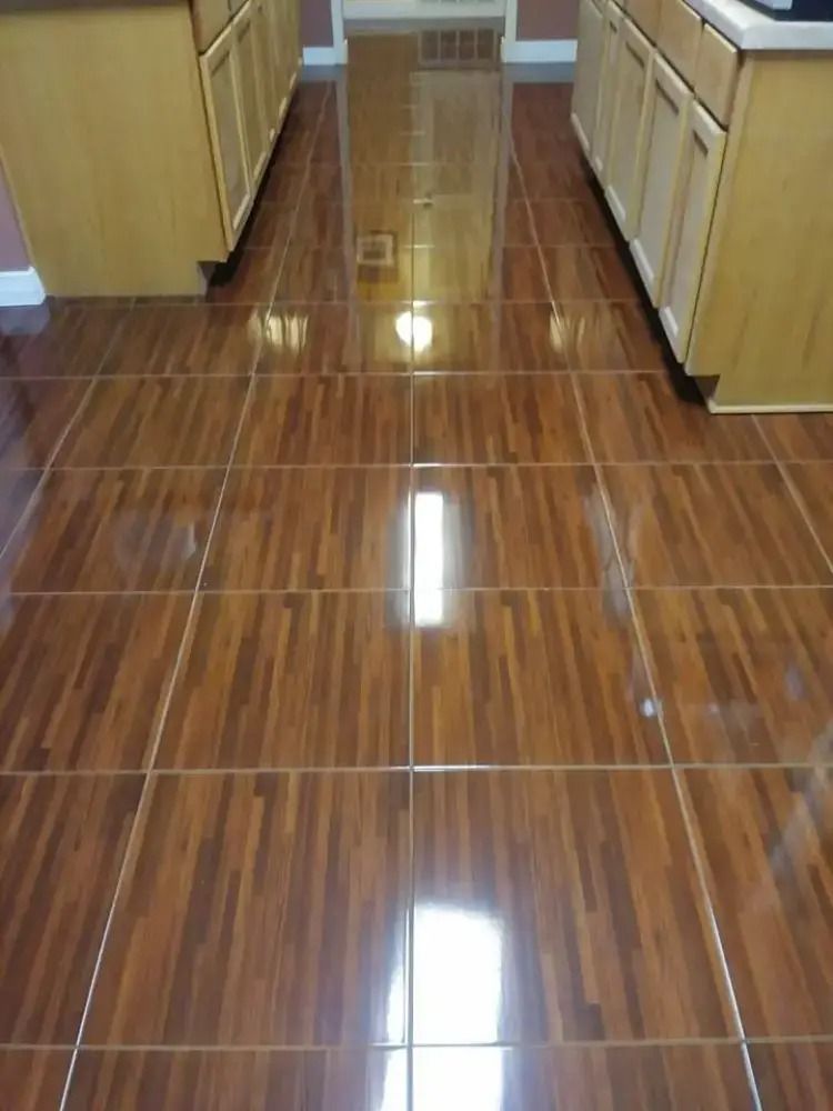Shiny brown tiled kitchen floor with light wood cabinets on both sides