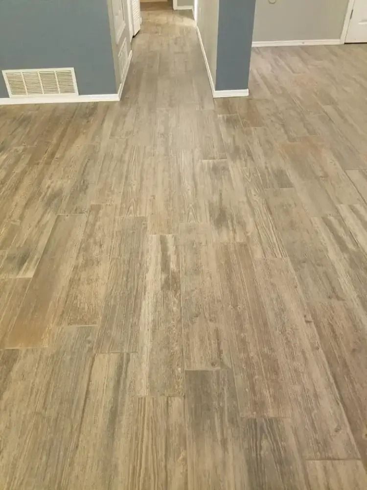 Empty room with light wood flooring and gray walls, viewed toward a doorway and vent