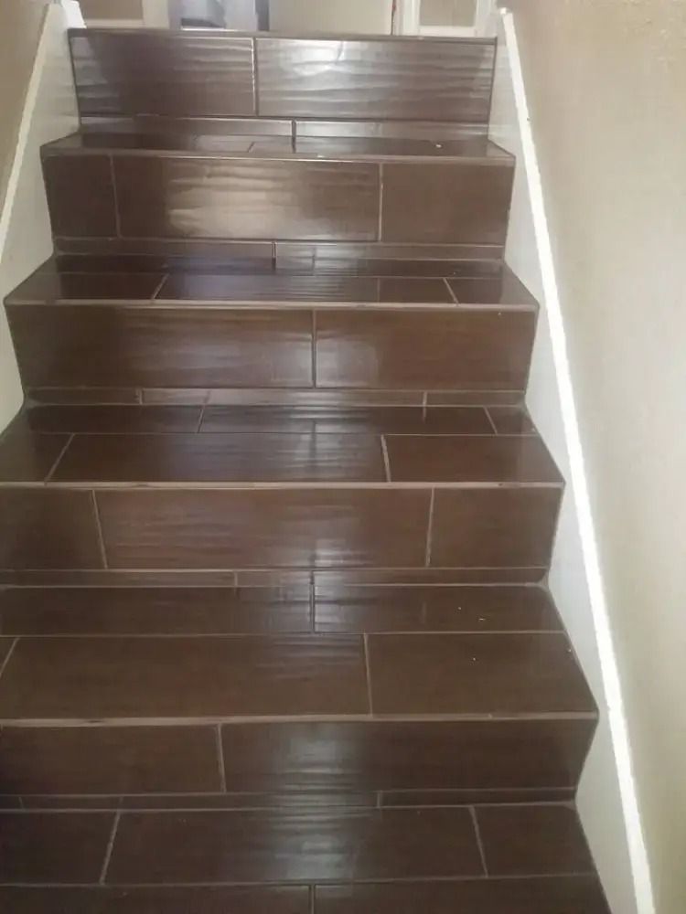 Dark brown tiled staircase with a white wall on the right.