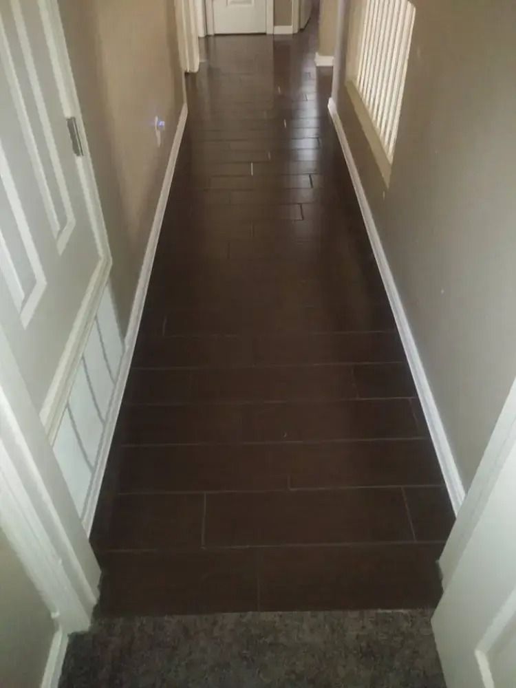 Narrow hallway with dark wood floor, white doors, and windows along the right wall