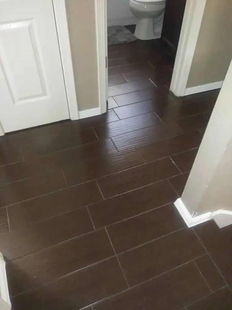 Dark brown tiled hallway leading to a bathroom with white doors and beige walls