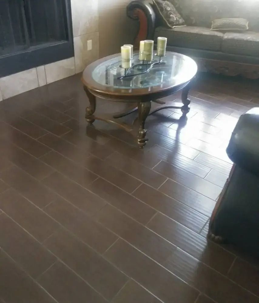 Living room with dark wood floor, round glass coffee table, and sofa with candles on top