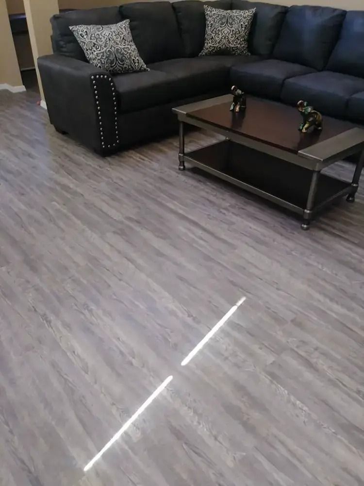 Living room with a black sectional sofa, coffee table, and gray wood-look flooring