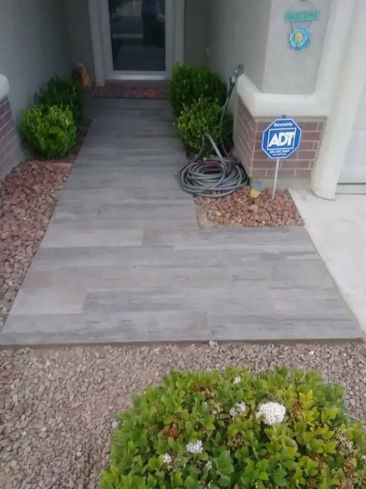 Front porch with gray tile walkway, potted shrubs, and an ADT security sign beside the entrance.