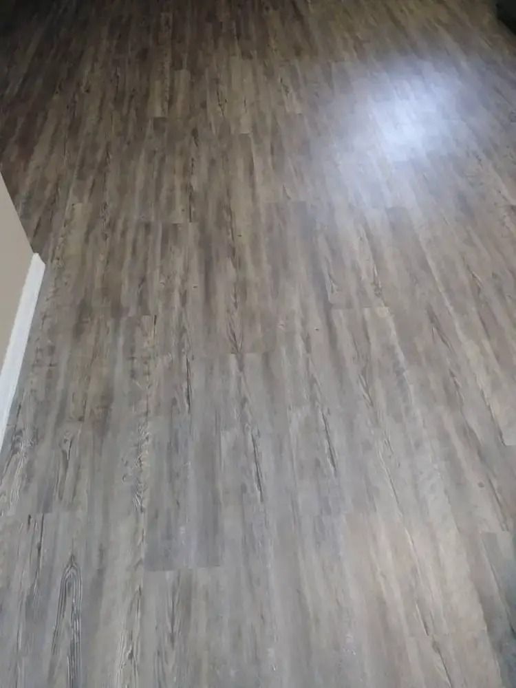 Empty wood-patterned floor with sunlight reflecting on the surface.