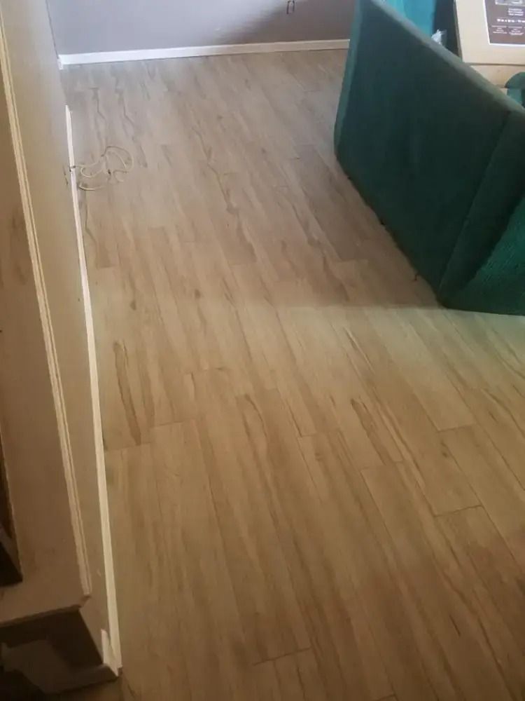 Wooden floor hallway beside a green cushioned bench and a doorway