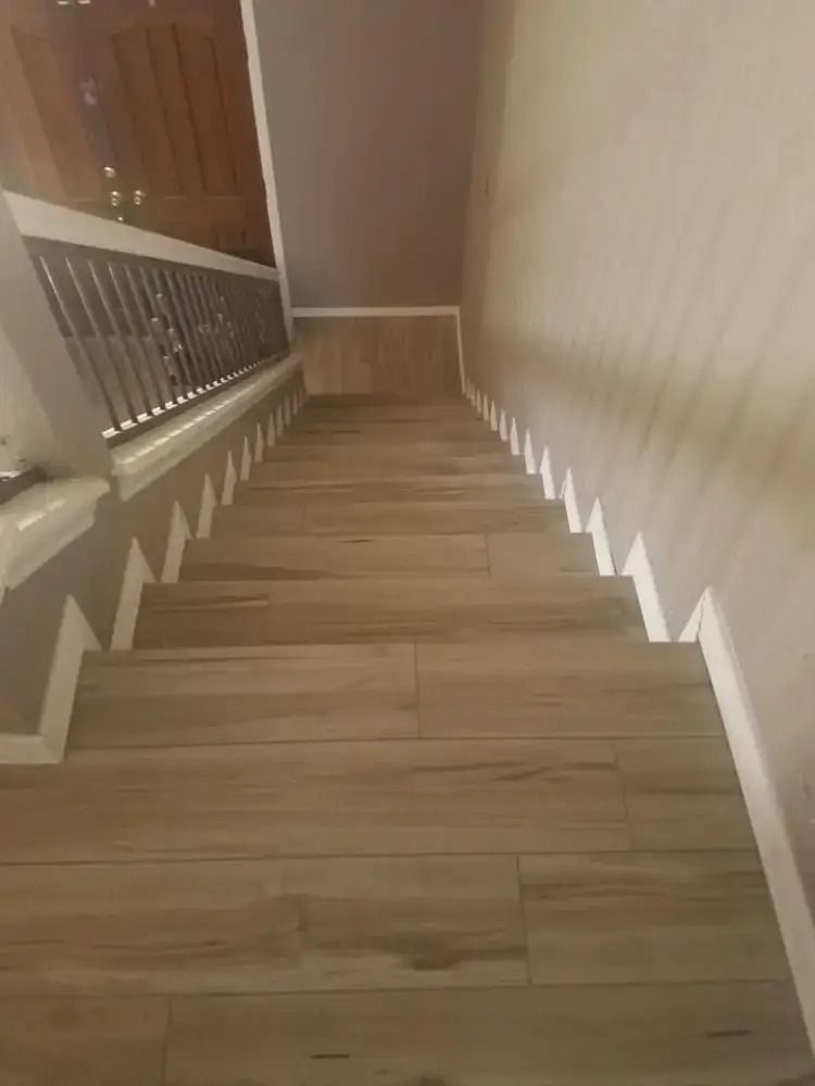 Staircase with light wood steps and beige walls, viewed from the top landing.