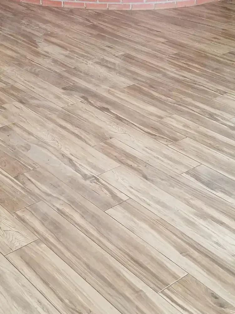 Light wood plank flooring with a curved pink brick edge at the top.