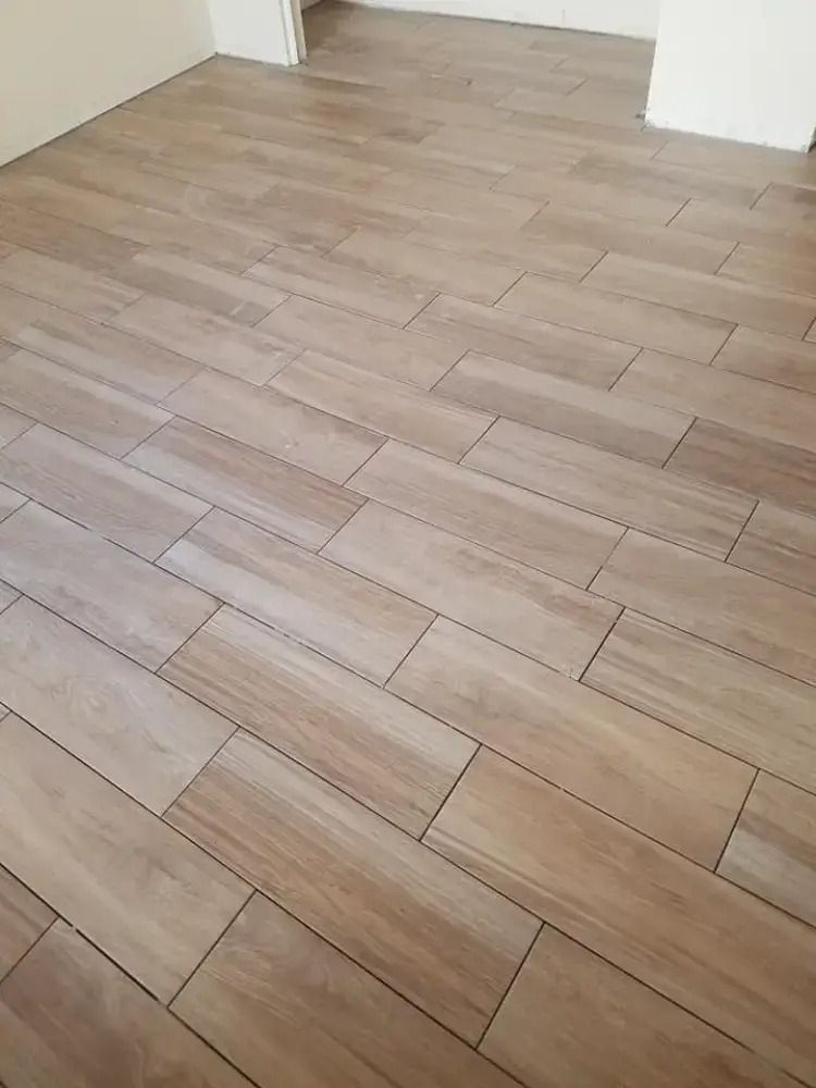 Light wood-look tiled floor in a mostly empty room with white walls and doorways