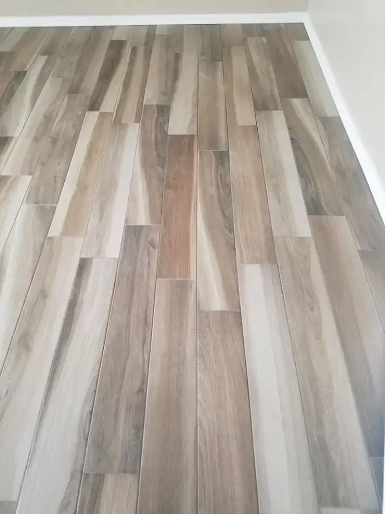 Empty room with light wood-pattern laminate flooring and white baseboards
