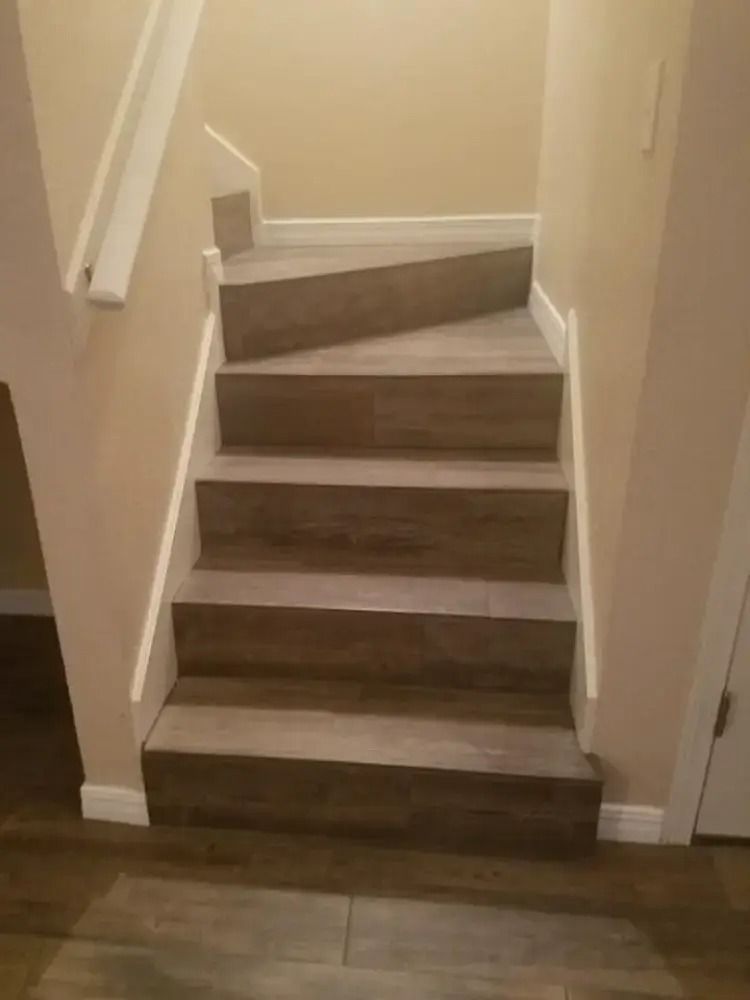 Narrow indoor staircase with beige walls and dark wood steps leading up to a landing