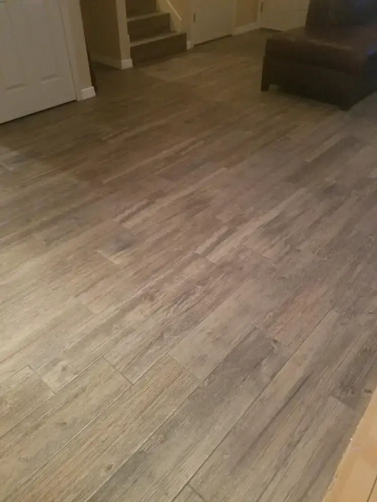 Empty wood-floored living room with stairs and a dark sofa in the corner
