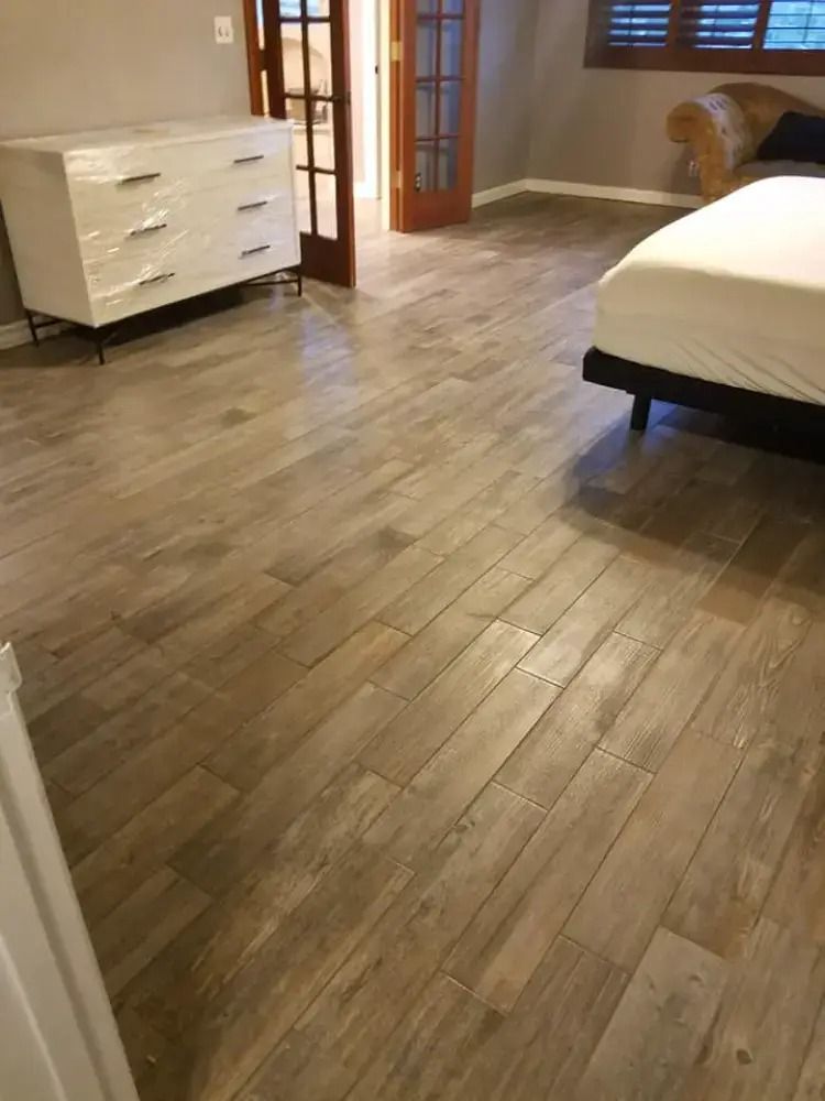 Bedroom with wood flooring, white dresser, bed, and open glass doors.