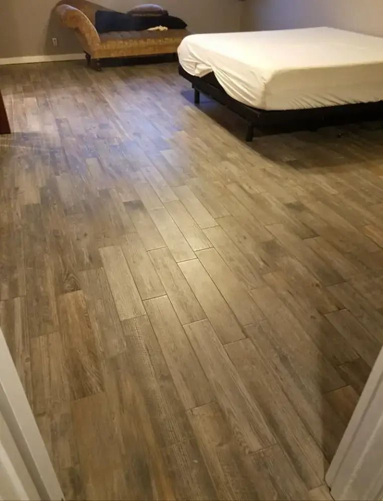 Spacious bedroom with wood flooring, two beds, and warm lighting.