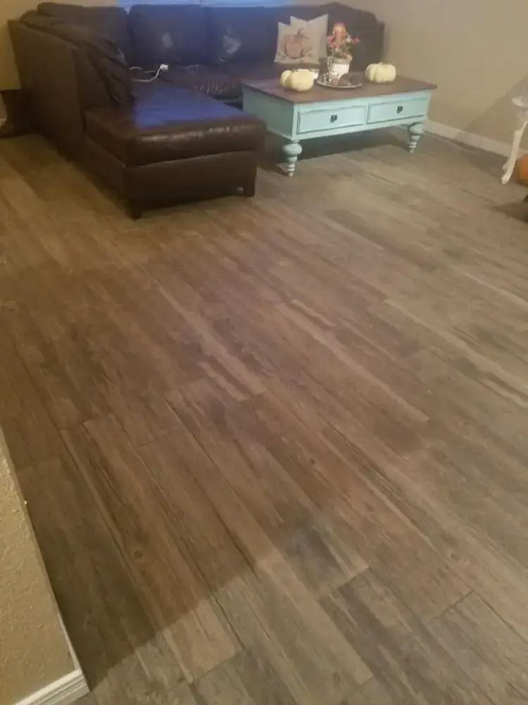 Living room with a dark sectional sofa, blue coffee table, and wood-look flooring