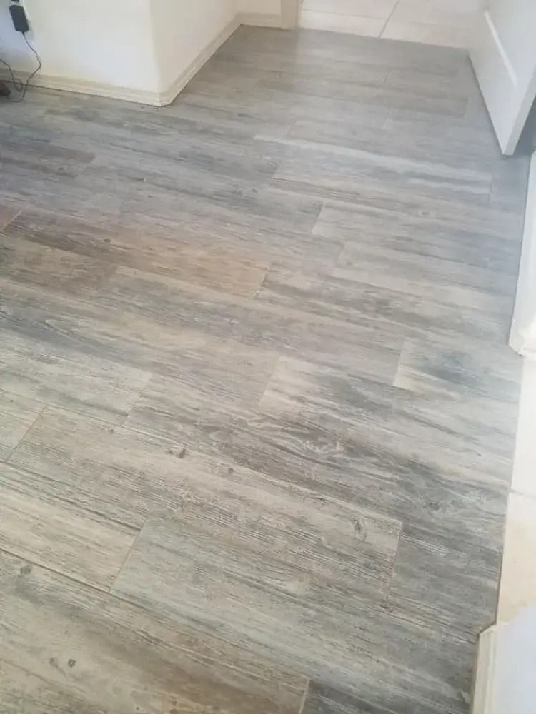 Light gray wood-look flooring in a hallway or room corner with white walls and baseboards